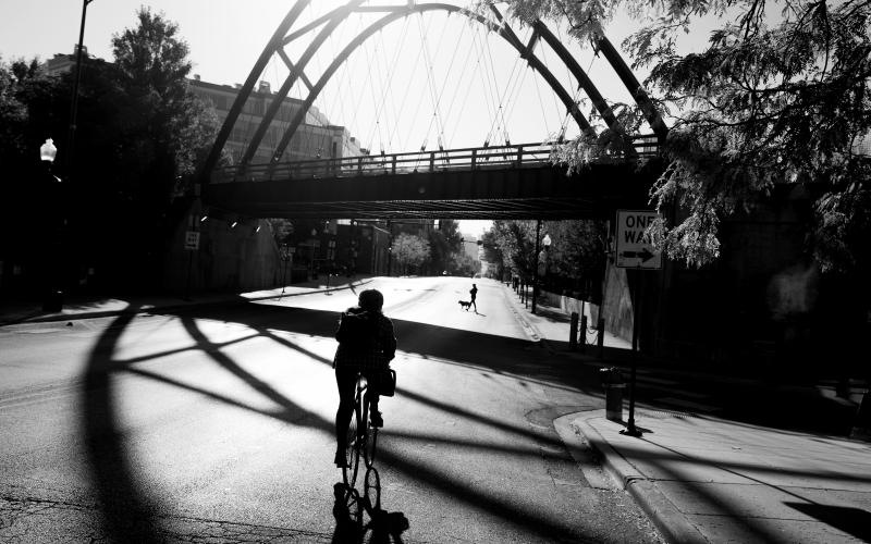 a person riding a bicycle under a bridge